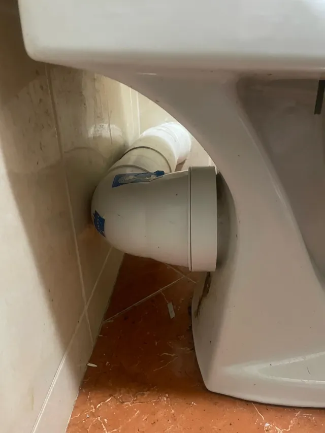 Pipe d'évacuation neuve raccordée derrière la cuvette