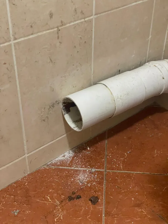 Tuyau d'évacuation en PVC découpé le long d'un mur carrelé